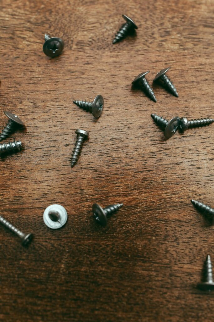 Detailed image of metal screws scattered on a wooden surface, ideal for carpentry-themed projects.